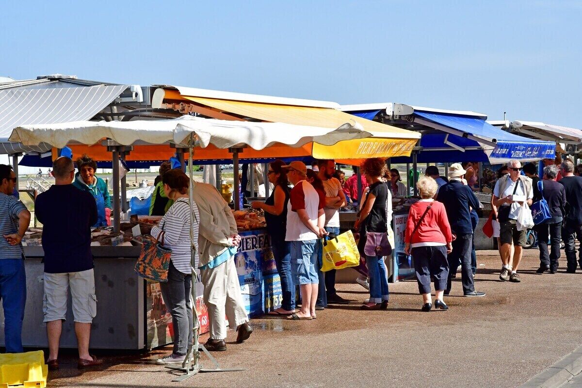 Ein belebter Markt im Freien mit verschiedenen Ständen und Einkäufern.