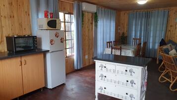 A wooden-paneled kitchen with a microwave, refrigerator, and a small dining table with chairs.
