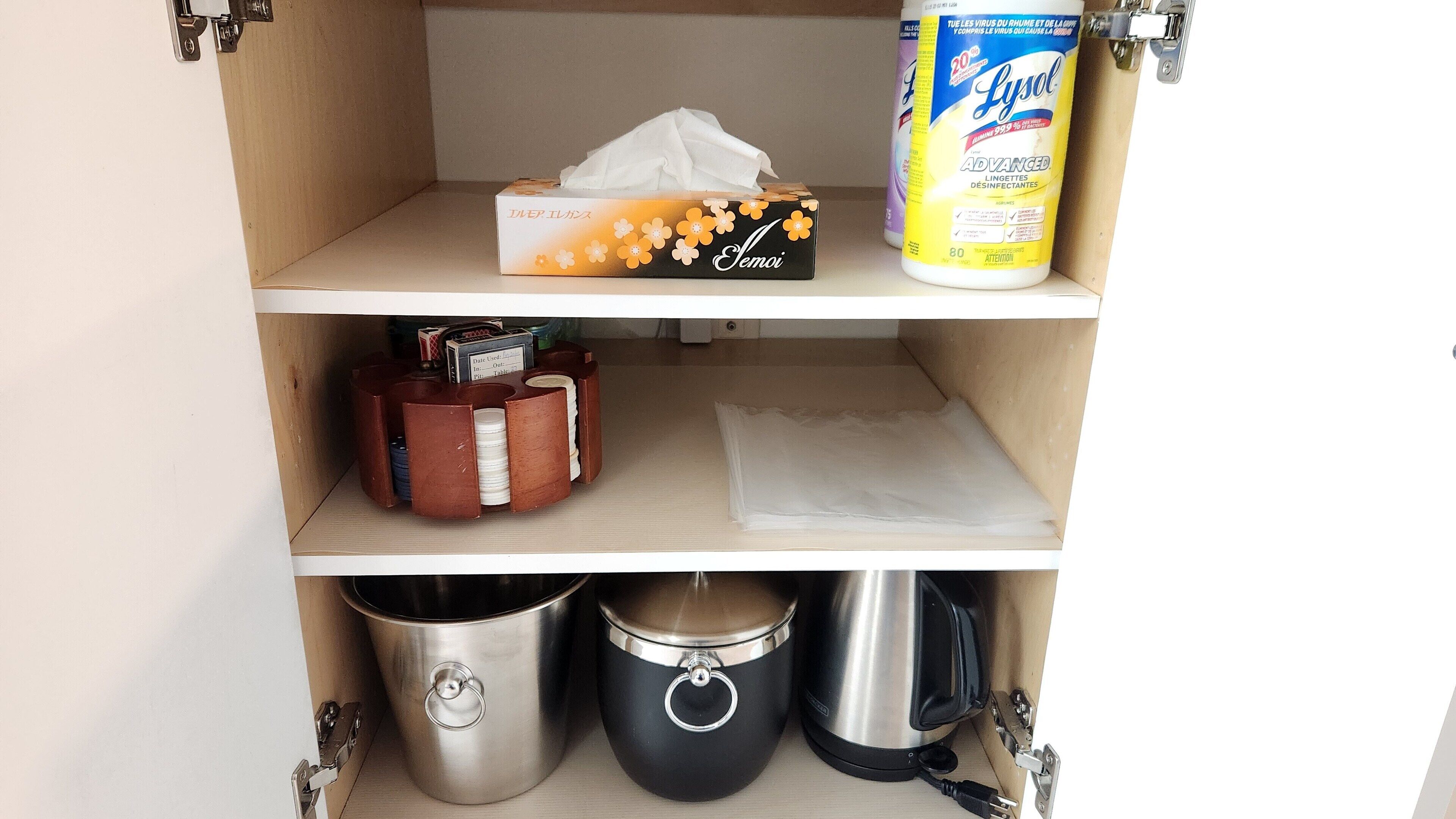 A kitchen cabinet with a tissue box, a Lysol disinfectant spray, and two stainless steel pots.
