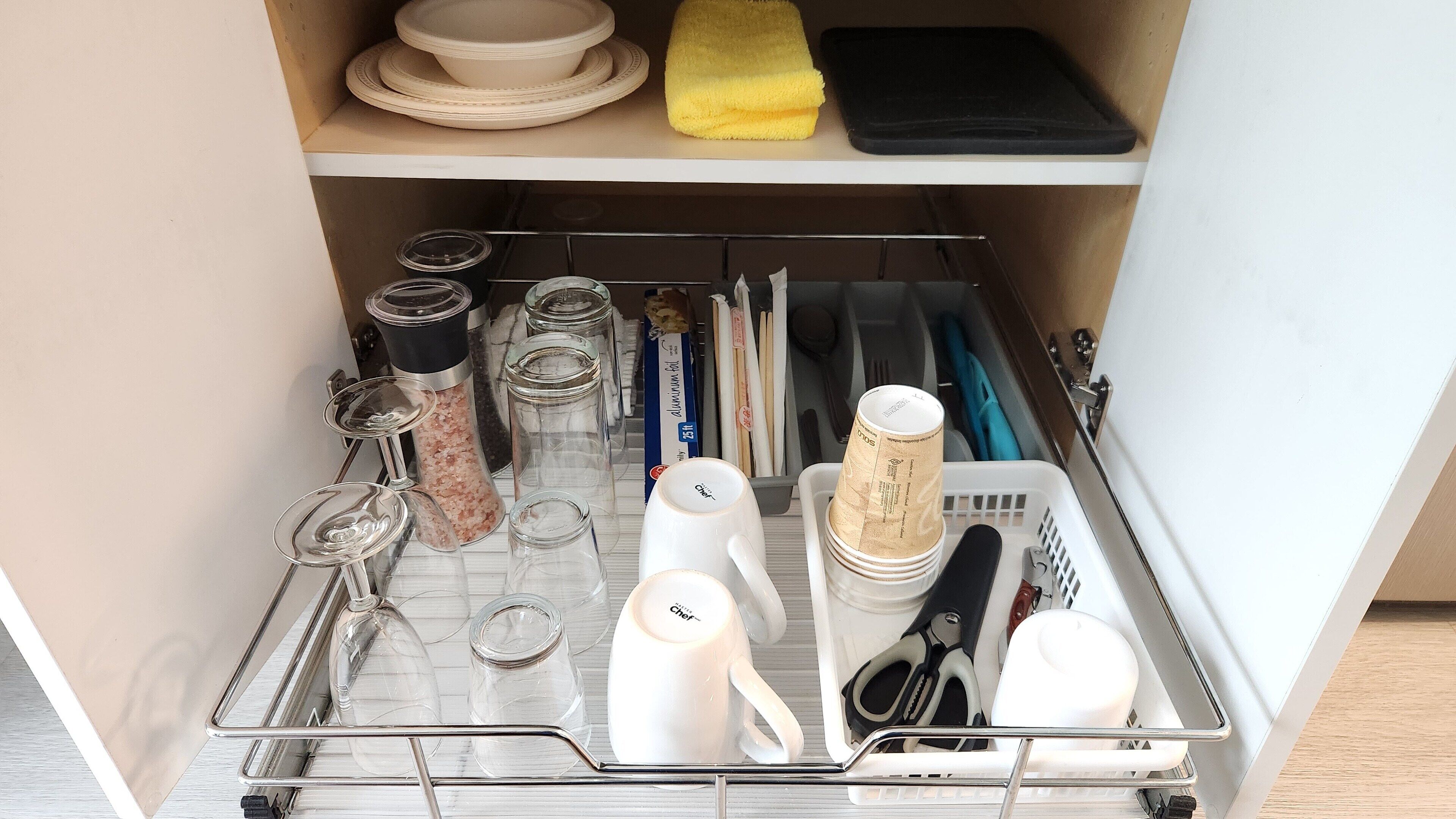 A kitchen cabinet with various utensils, cookware, and storage containers.