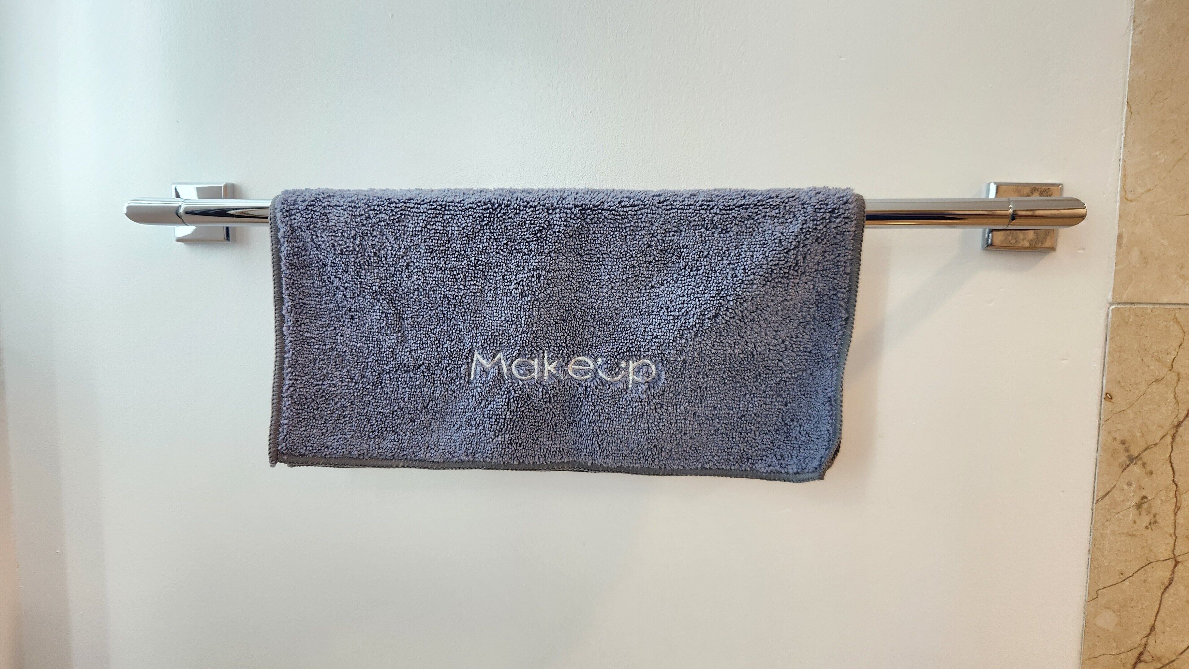 Une salle de bain avec une serviette suspendue à un porte-serviettes en métal.