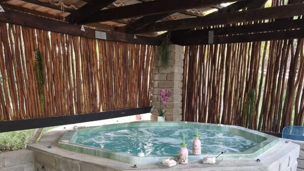 A hot tub with a brick base, surrounded by a bamboo fence and a stone wall. - Klein Huisie Little House Self Catering Africa Bush Vacation In Marloth Park (Nkomazi)