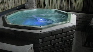 A hot tub with a brick base and a glass top, surrounded by a bamboo wall. - Klein Huisie Little House Self Catering Africa Bush Vacation In Marloth Park (Nkomazi)