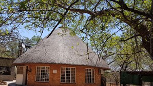 A thatched-roof house with brick walls, a satellite dish, and a sign indicating it is a museum. - Klein Huisie Little House Self Catering Africa Bush Vacation In Marloth Park (Nkomazi)