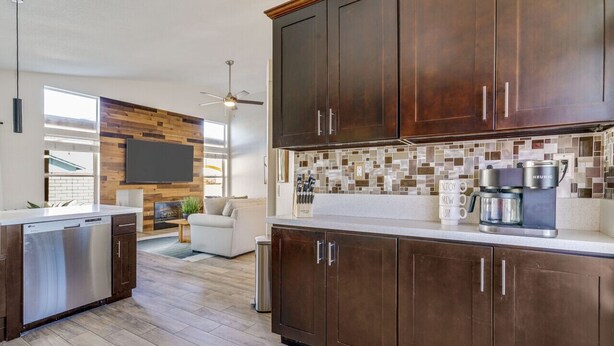 A modern kitchen with dark wood cabinets, a tiled backsplash, and a built-in dishwasher. - Palmas de Indio: Pool, Private, Walk to Festivals (Indio)