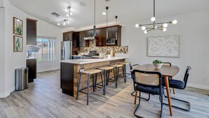A modern kitchen with a central island, bar stools, and pendant lighting. - Palmas de Indio: Pool, Private, Walk to Festivals (Indio)