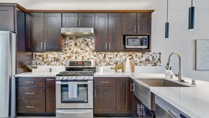 A modern kitchen with dark wood cabinets, a stainless steel range, a microwave, and a dishwasher. - Palmas de Indio: Pool, Private, Walk to Festivals (Indio)