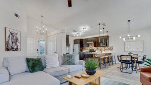 A modern living room with a sofa, coffee table, and a dining area with chairs and a table. - Palmas de Indio: Pool, Private, Walk to Festivals (Indio)