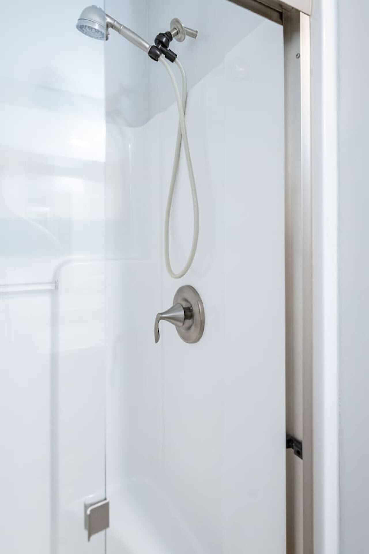 Une douche moderne dotée d’un pommeau de douche à main et d’un robinet de contrôle fixé au mur.