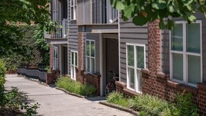 A modern multi-story residential building with a brick facade, large windows, and a covered outdoor area. - Modern 1BR Flat: Free Parking, AC, Getaway Ready! (Lynchburg)