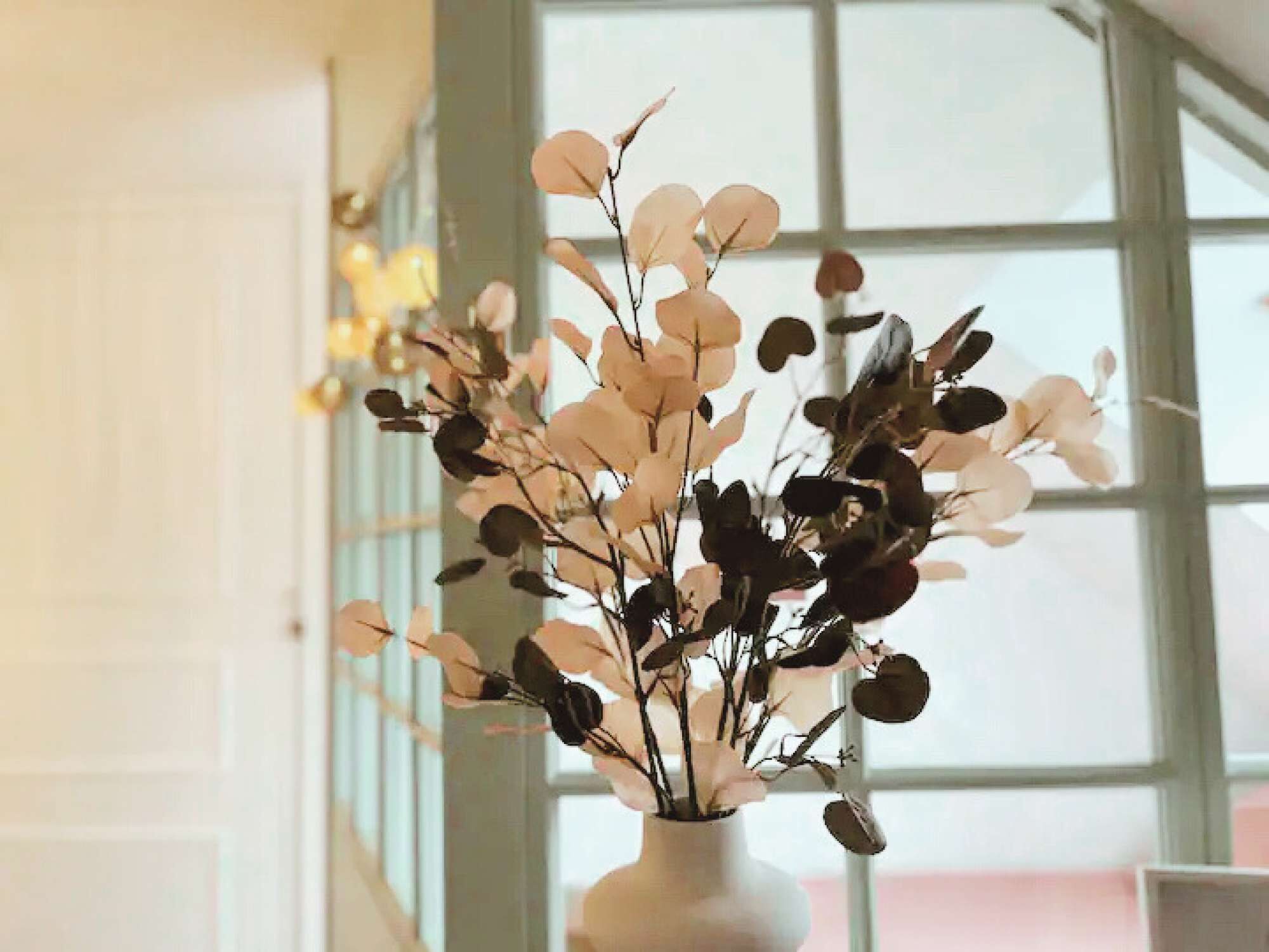 A vase with a floral arrangement in a room with large windows.