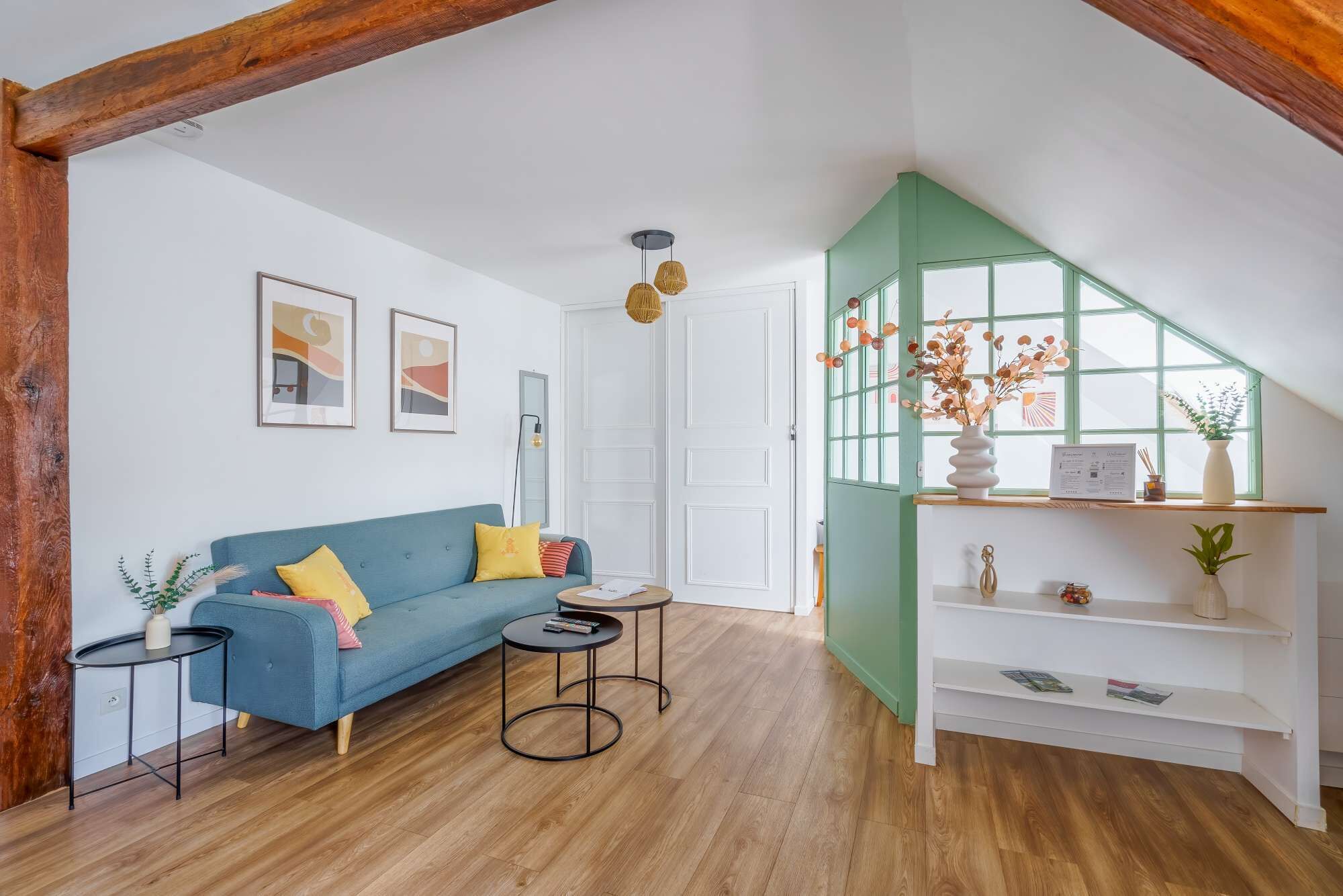 Una sala de estar con un sofá azul, una mesa de centro redonda y una estantería.