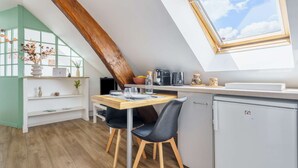 Eine kompakte Küche mit Essbereich, Holzboden und einem Fenster zum Himmel.