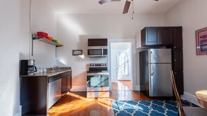 Una cocina moderna con electrodomésticos de acero inoxidable, piso de madera y ventilador de techo.