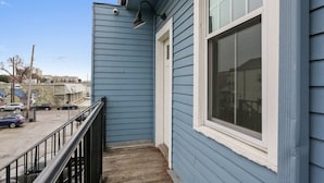Une façade bleue avec une fenêtre et un petit balcon doté d’une rambarde noire.