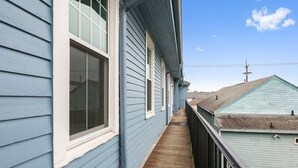 Une étroite terrasse en bois, dotée d’une rambarde en métal, mène à un bâtiment dont le revêtement est bleu et les bordures, blanches.