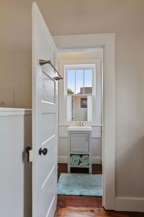 A bathroom with a white door, a window, a sink, and a towel rack. - Delightful Freret St Studio Apartment w/parking (New Orleans)