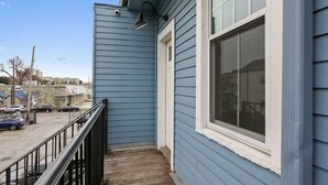 Ein blaues Gebäude mit Fenster und einem kleinen Balkon mit schwarzer Geländer.