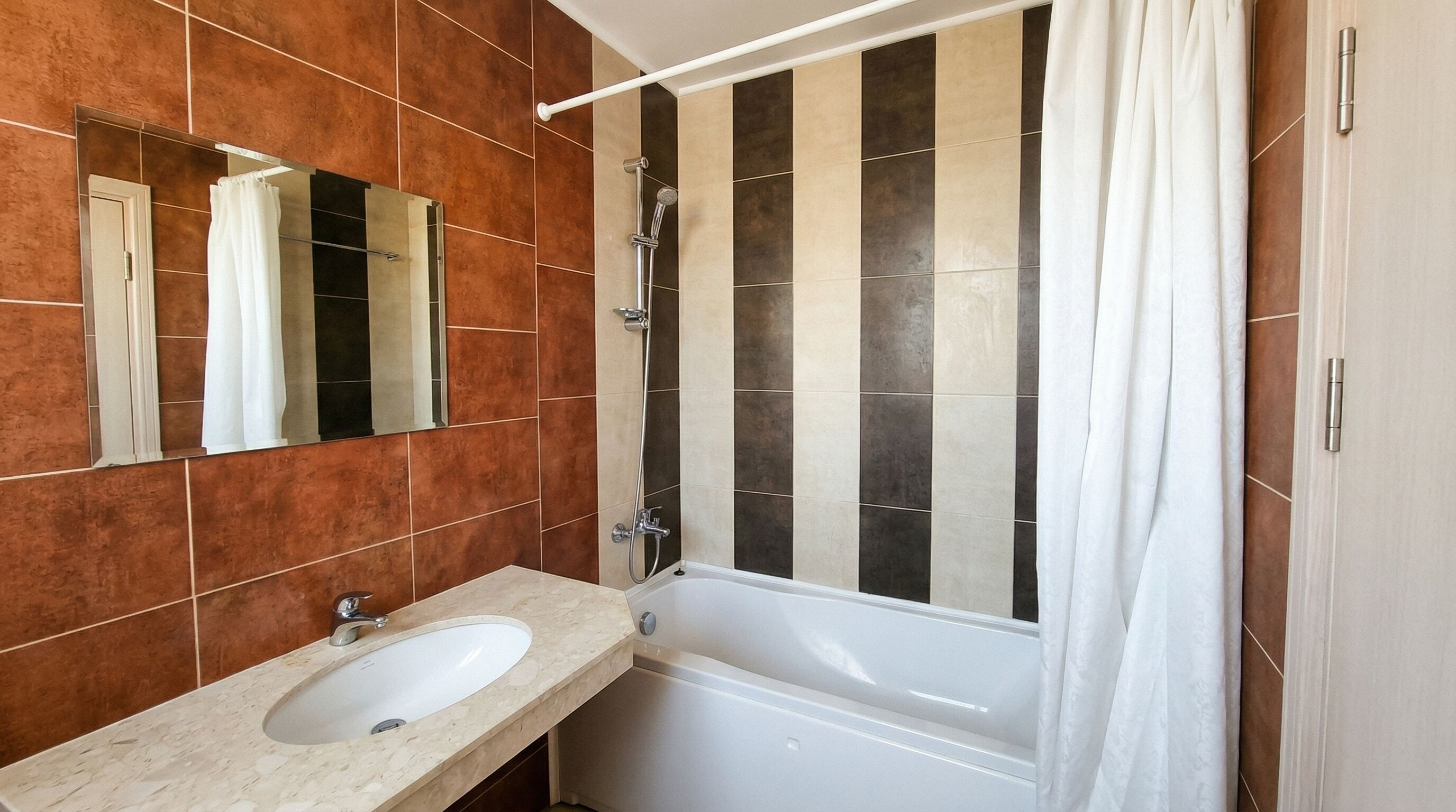 A bathroom with a white bathtub, a sink, and a shower with a curtain.