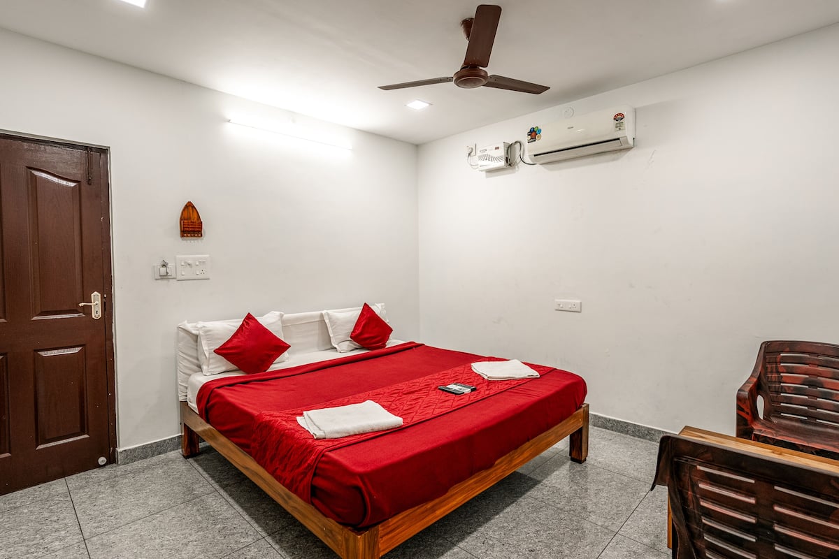Un dormitorio con cama, ventilador de techo, aire acondicionado y puerta de madera.