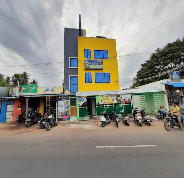 A multi-story building with a yellow and grey facade, several windows, and a sign for a French Park Inn. - French Park Inn (Vanur)