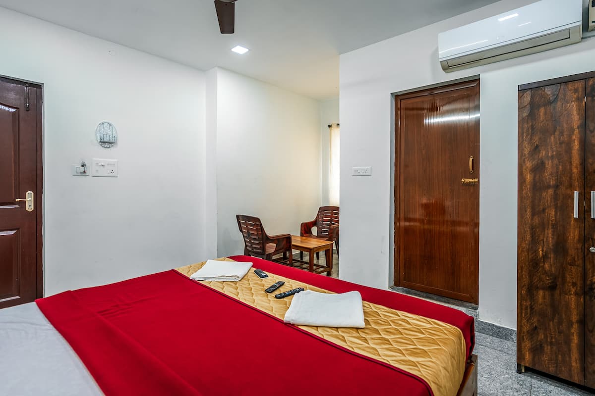 Habitación de hotel con una cama, un escritorio y dos sillas. Hay un equipo de aire acondicionado en la pared.