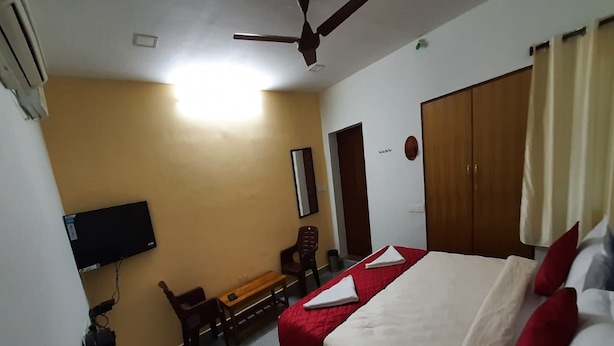 Una habitación de hotel con cama, escritorio, silla, televisor y armario.