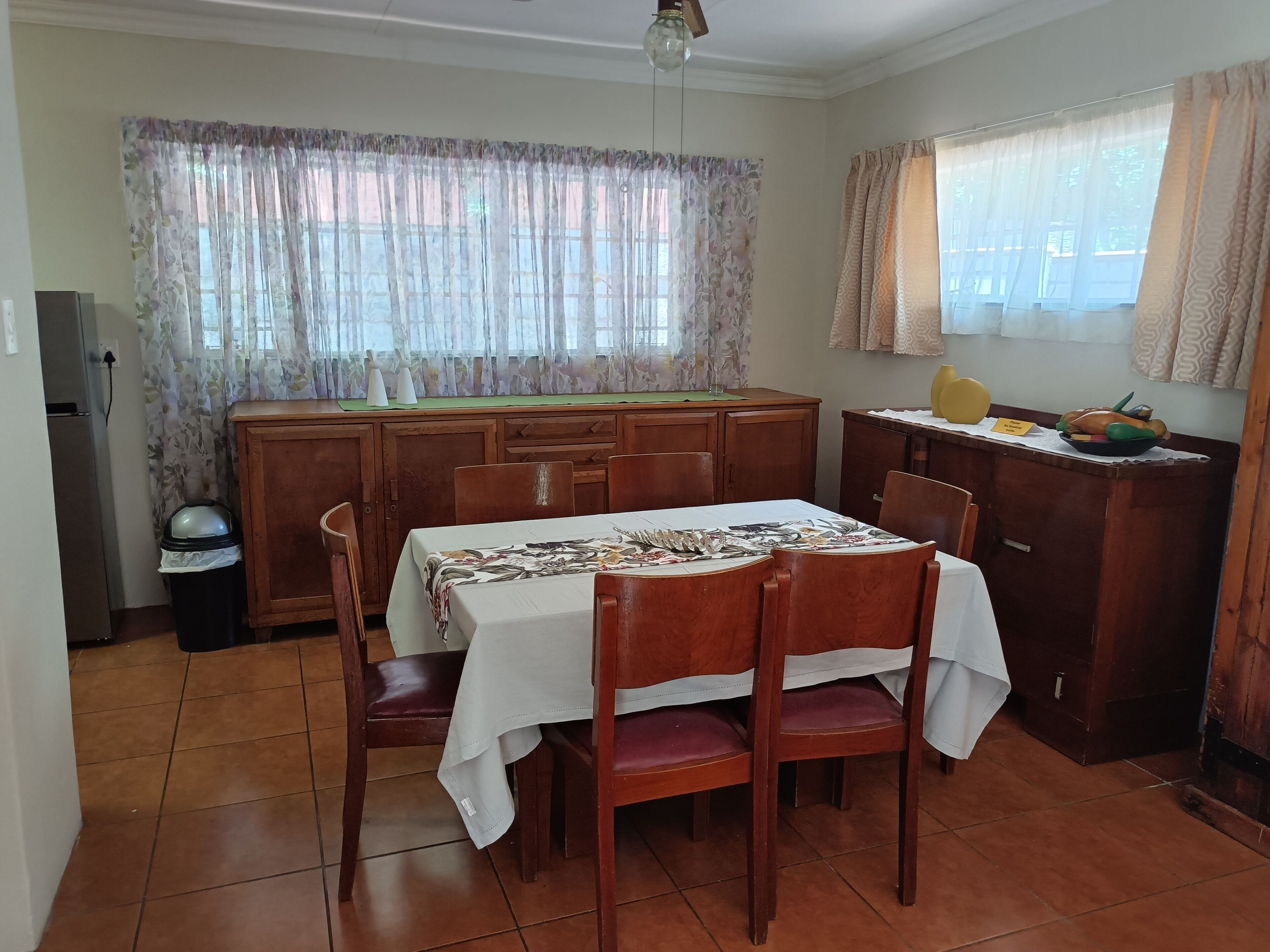 Un comedor con una mesa y sillas de madera, una encimera de cocina y un ventanal con cortinas.