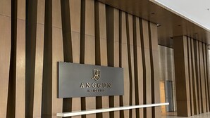 Une façade moderne avec un revêtement vertical en panneaux de bois et une enseigne pour Anggun Residences.