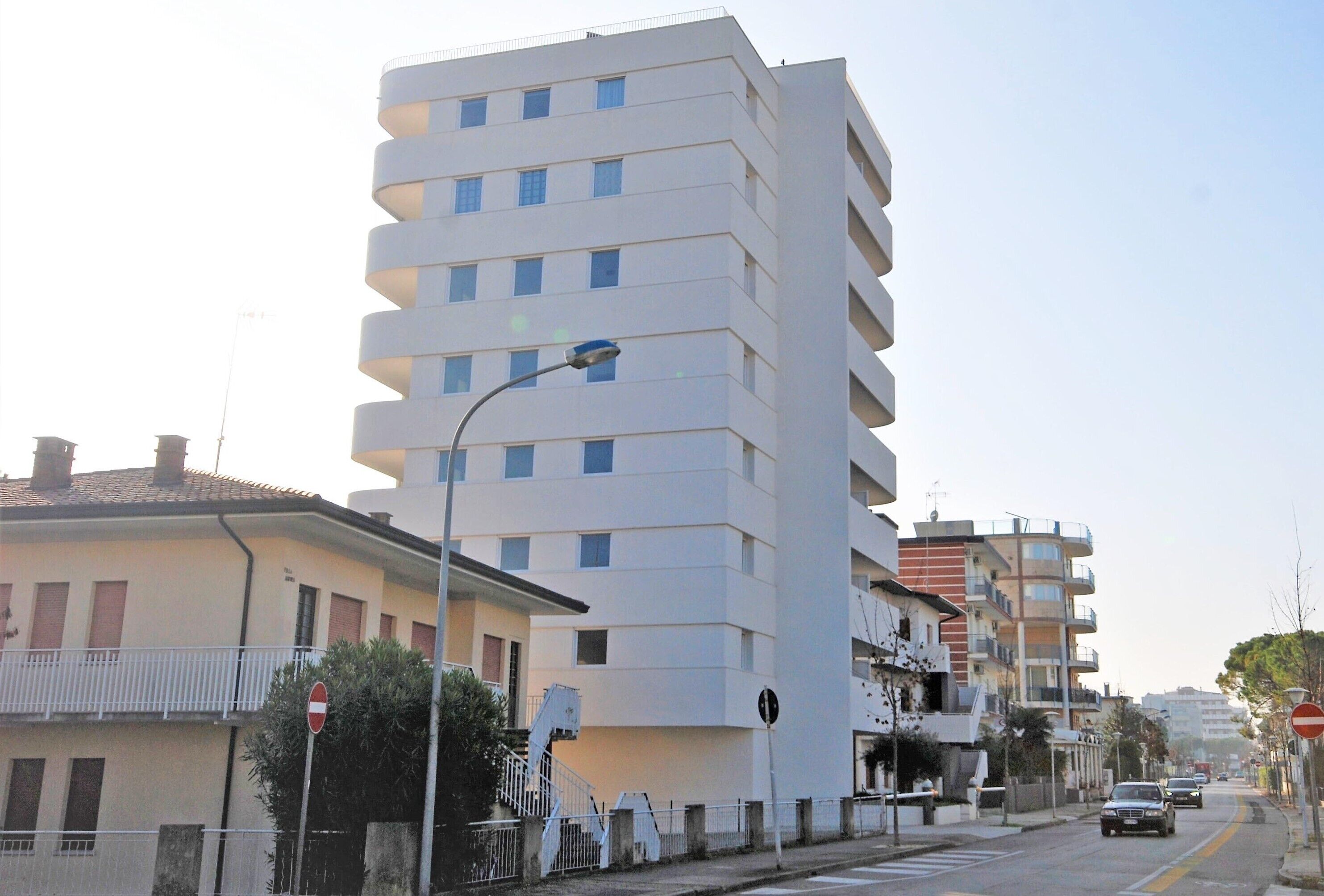Un edificio residencial de varios pisos con balcones, una farola y una señal de prohibido el paso.