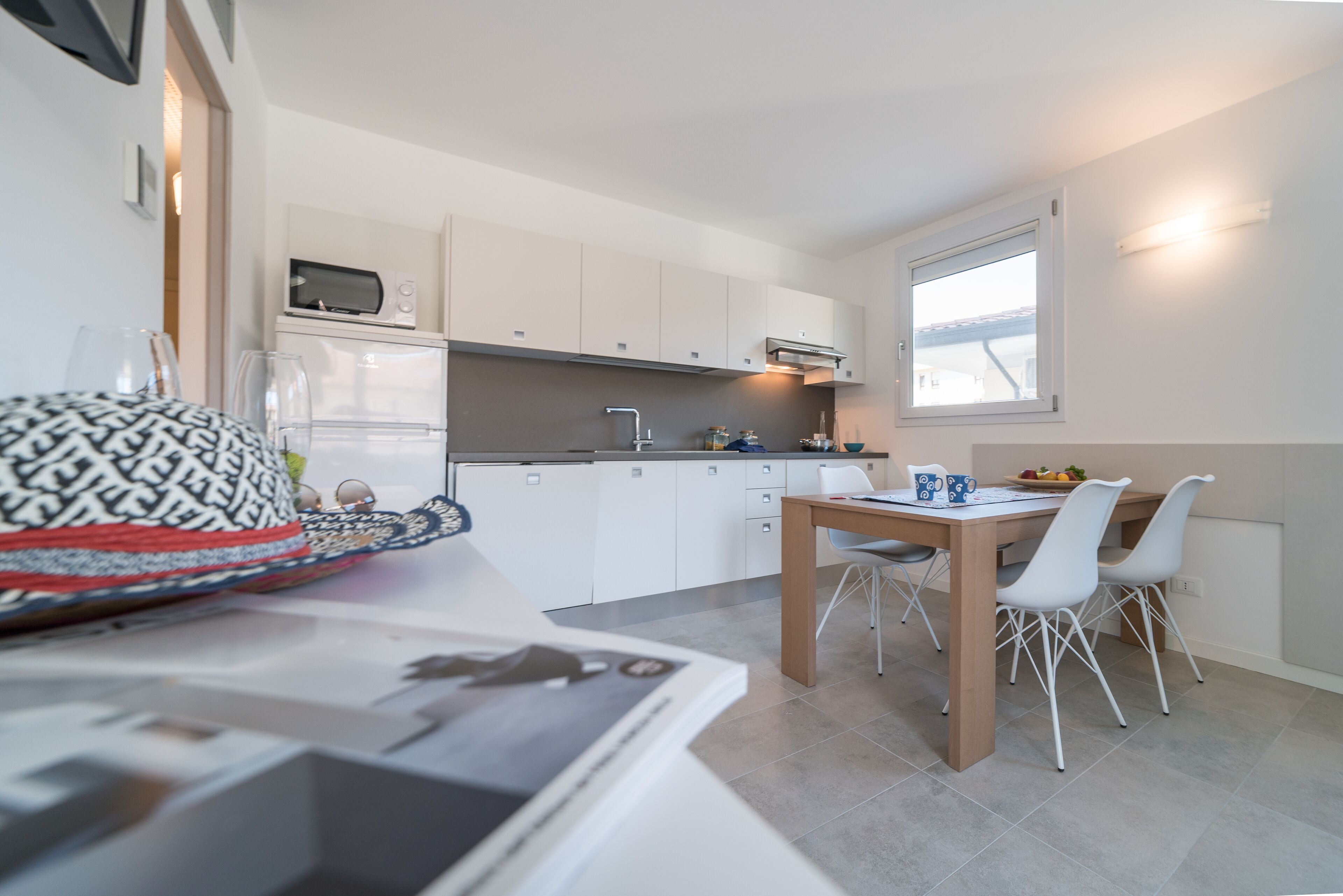 A compact kitchen with white cabinets, a microwave, and a dining area with a table and chairs.