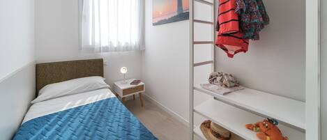 A bedroom with a bed, a nightstand, a shelf with a plush toy, and a painting of a lighthouse.