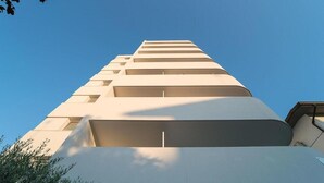 A tall, modern building with a series of balconies.