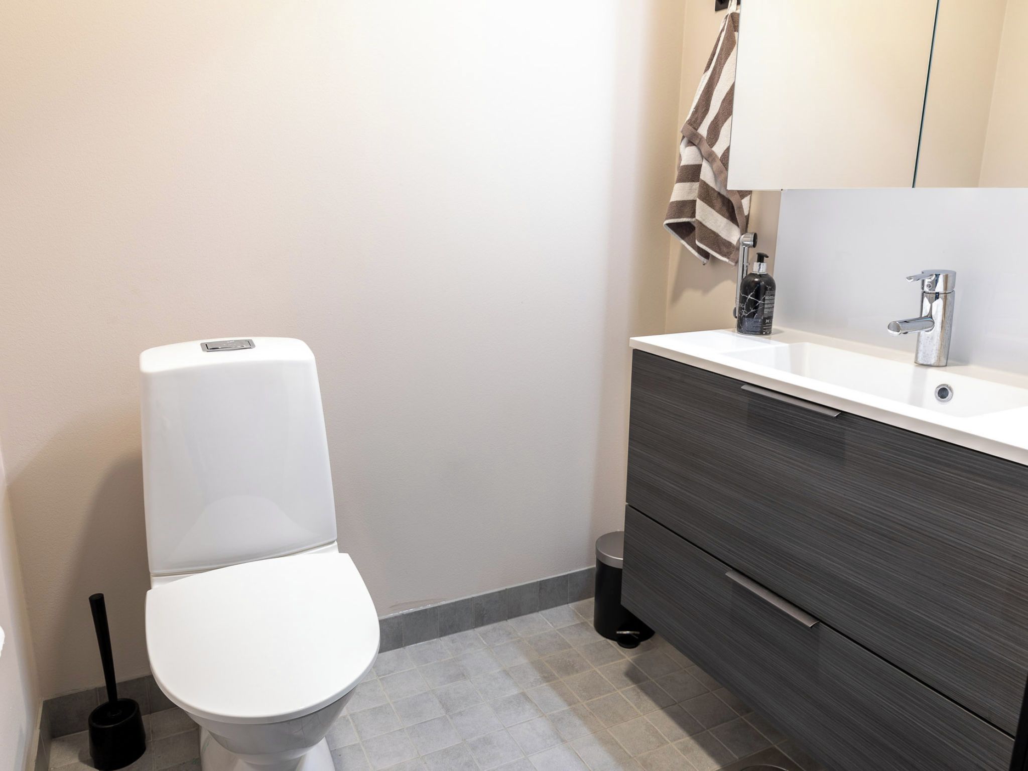 Moderni kylpyhuone, jossa on wc, pesuallas ja allaskaappi.