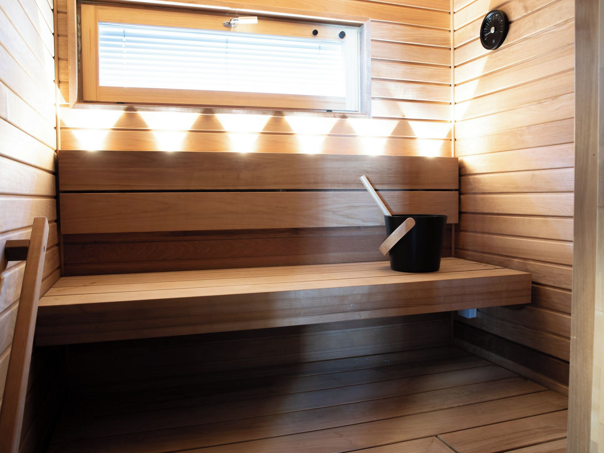 Un cuarto de sauna con bancos de madera, una ventana y un reloj en la pared.