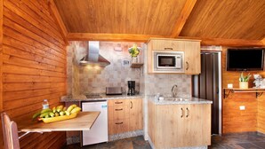 Een kleine keuken met houten kastjes, een magnetron, een fornuis en een spoelbak.