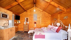 Een houten cabin met een keuken, een bed en een televisie.