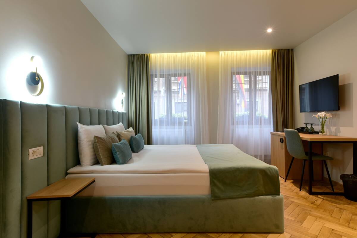 Une chambre d’hôtel moderne, dotée d’un grand lit, d’un bureau et d’une télévision.