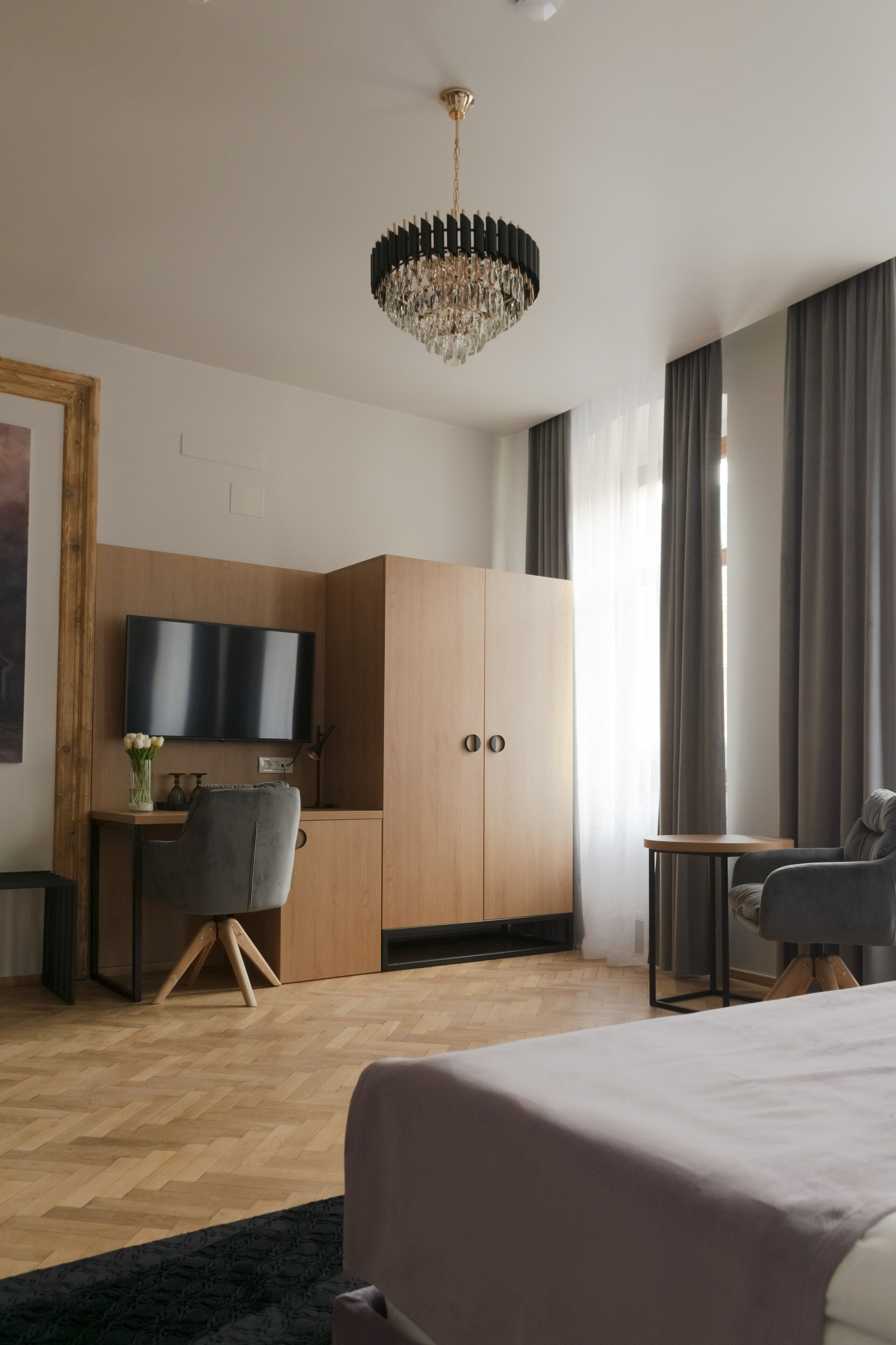 Una habitación de hotel moderna con una cama grande, un escritorio con una silla, televisión y armario.