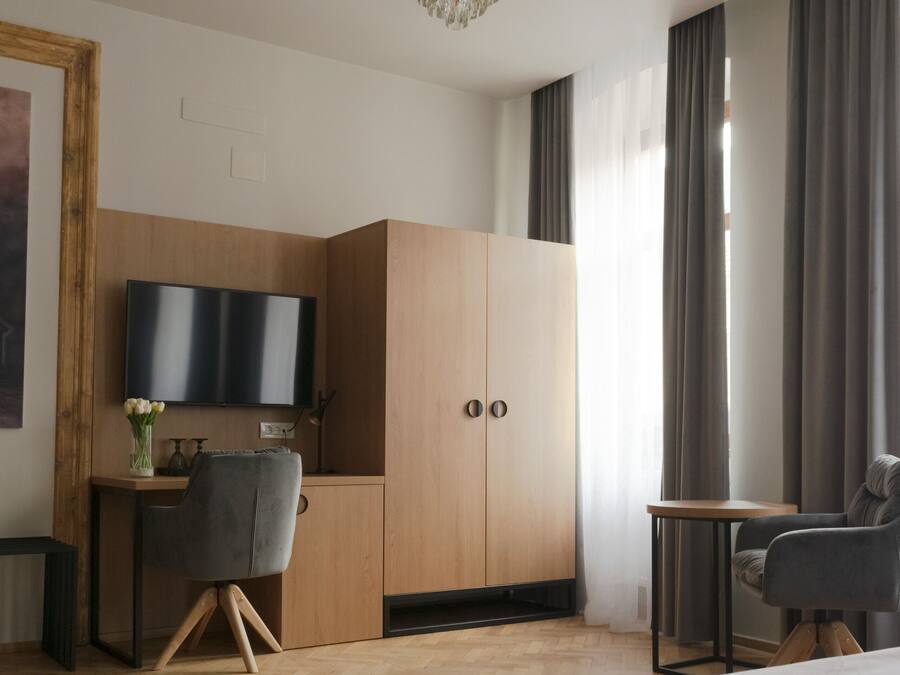 Et moderne hotelværelse med en stor seng, et skrivebord med stol, et fjernsyn og et klædeskab.