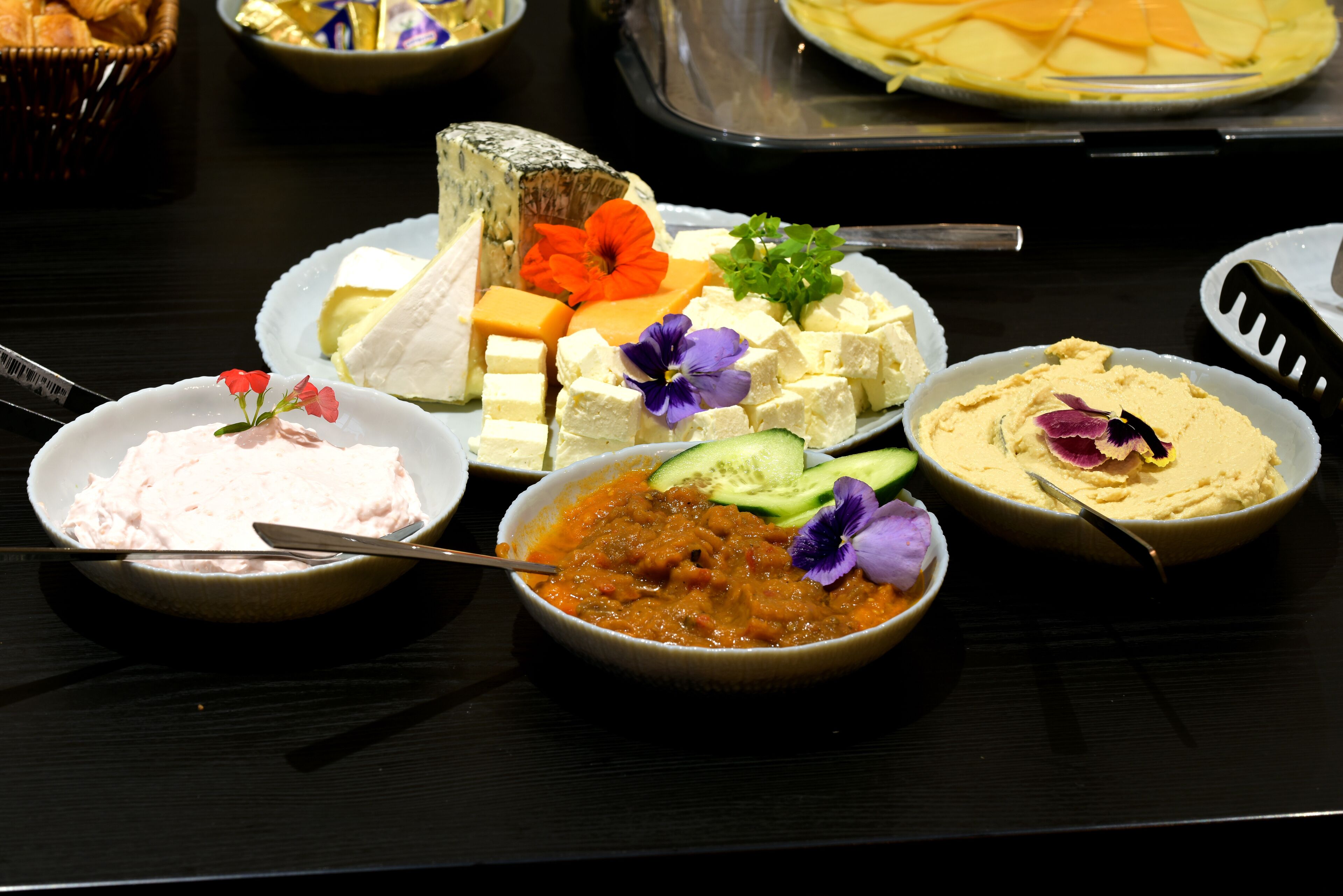 A table with various food items including cheese, vegetables, and dips.