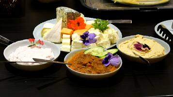 Una mesa con diferentes alimentos, incluyendo queso, verduras y salsas.