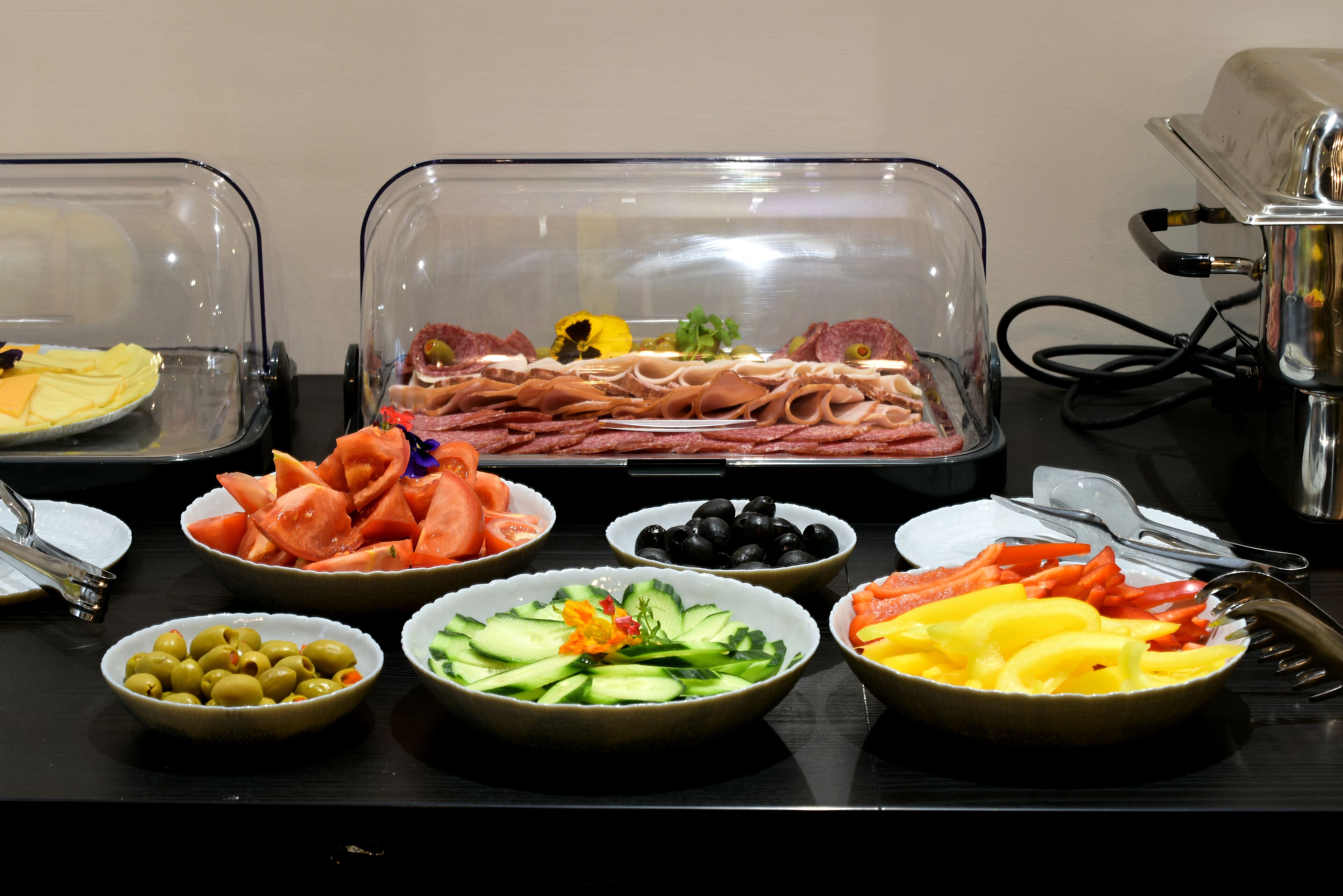 Une table de buffet proposant une variété d’aliments, notamment des viandes, des légumes et des fruits.
