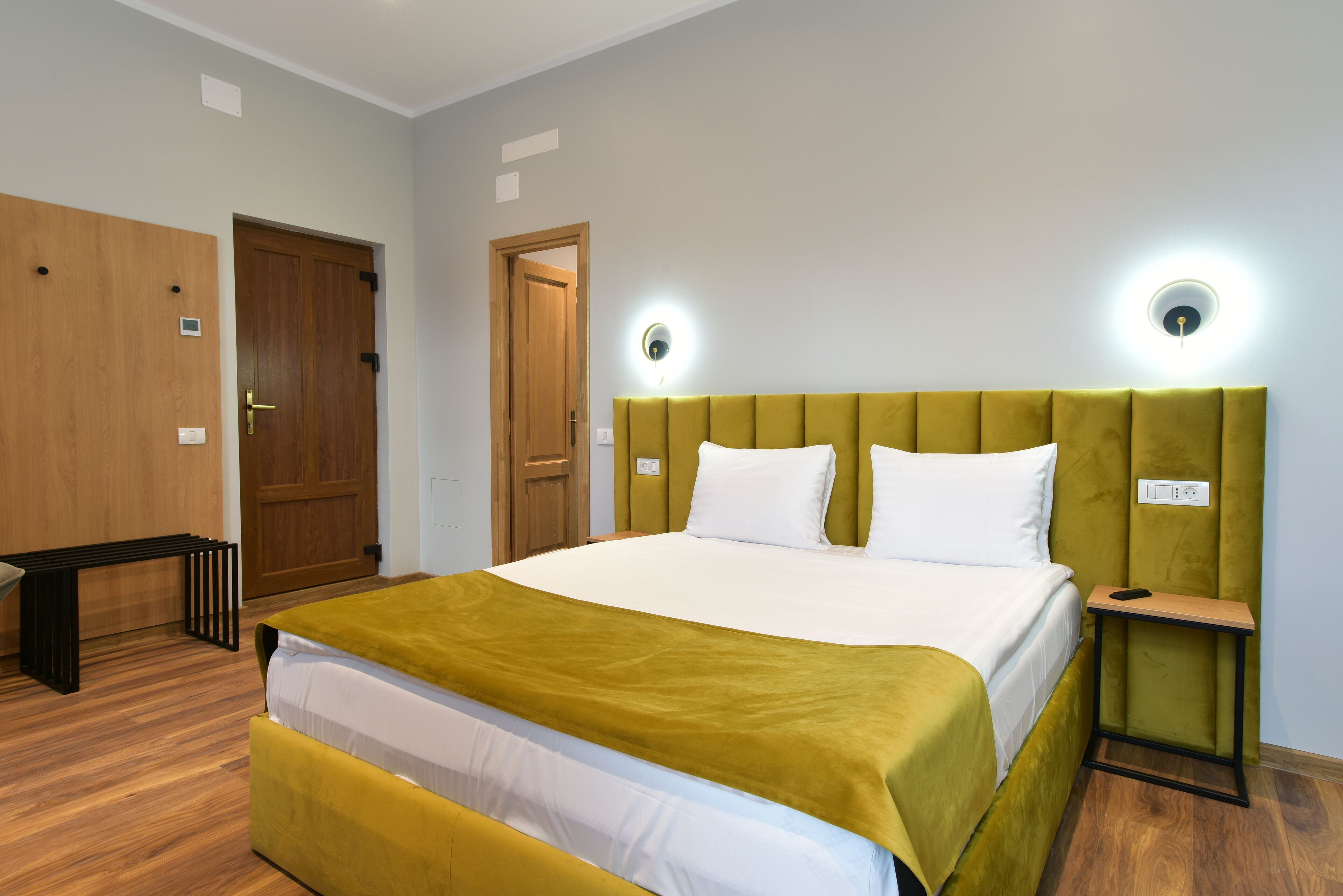 Une chambre d’hôtel avec un lit, une table de chevet et un banc.