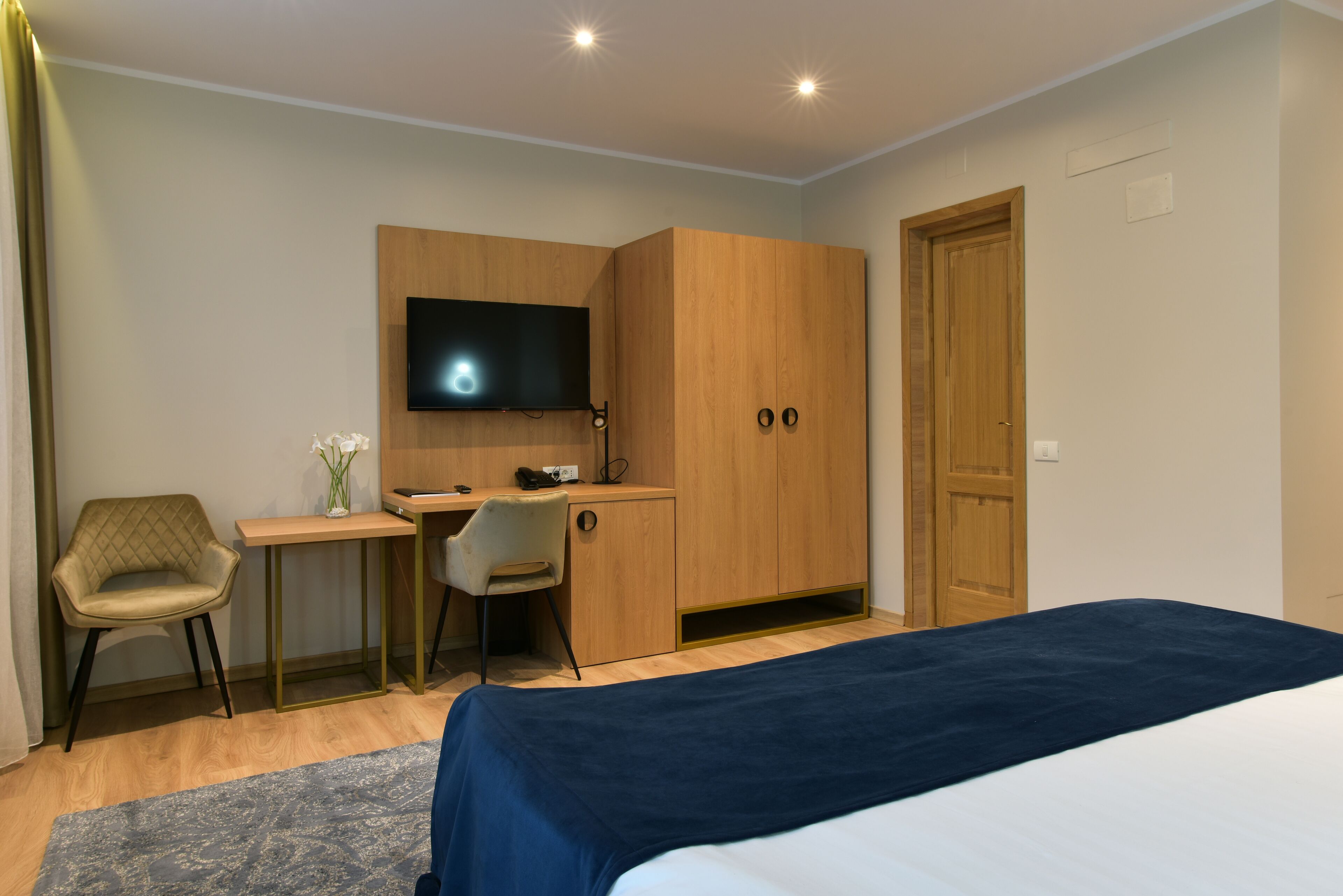 Un dormitorio con cama, escritorio, silla, televisor y armario.