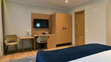 Un dormitorio con cama, escritorio, silla, televisor y armario.