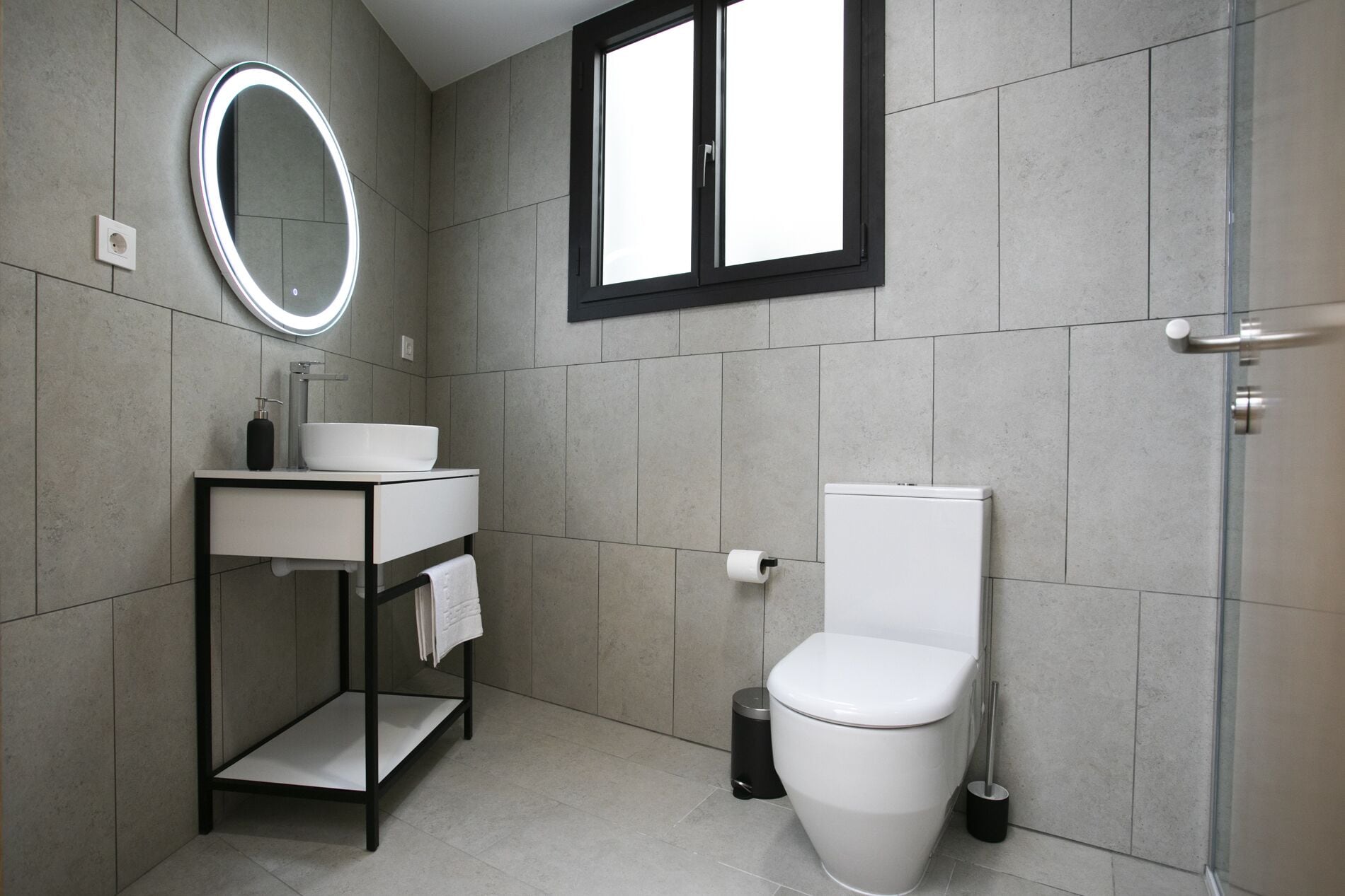 A modern bathroom with a white sink, mirror, and toilet.