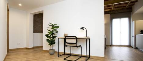 A minimalist office space with a wooden desk, a chair, a desk lamp, and a potted plant.