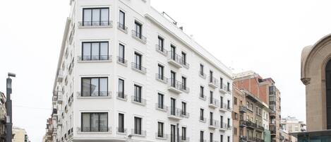 A multi-story building with balconies, a ground-level entrance, and a corner location.