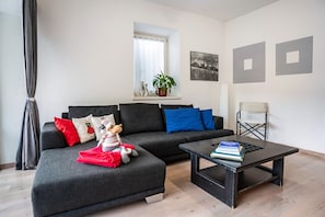 En moderne stue med en modulsofa, et sofabord og et vindue med en plante.